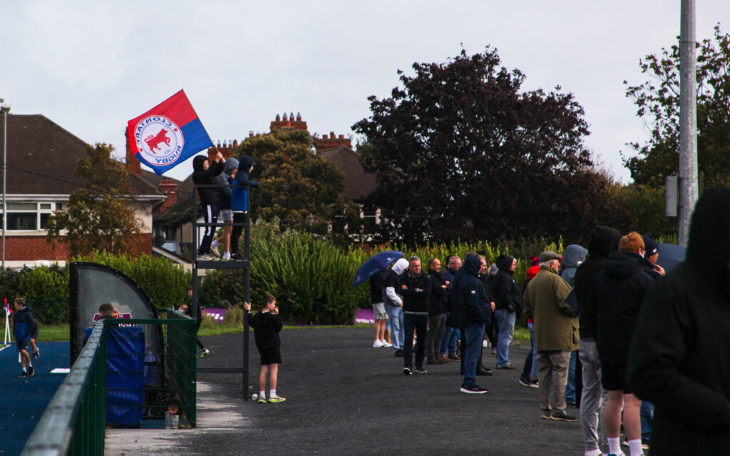 Young Clontarf supporters waving a club flag from a camera platform at Castle Avenue